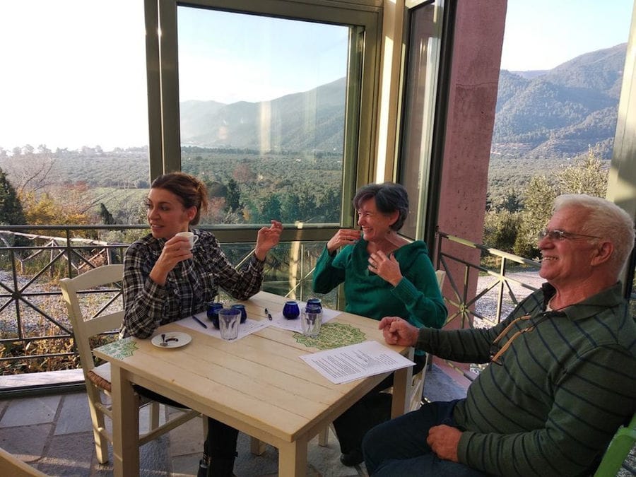 a man and two women smiling and watching something at 'Eleonas' and tasting olive oil